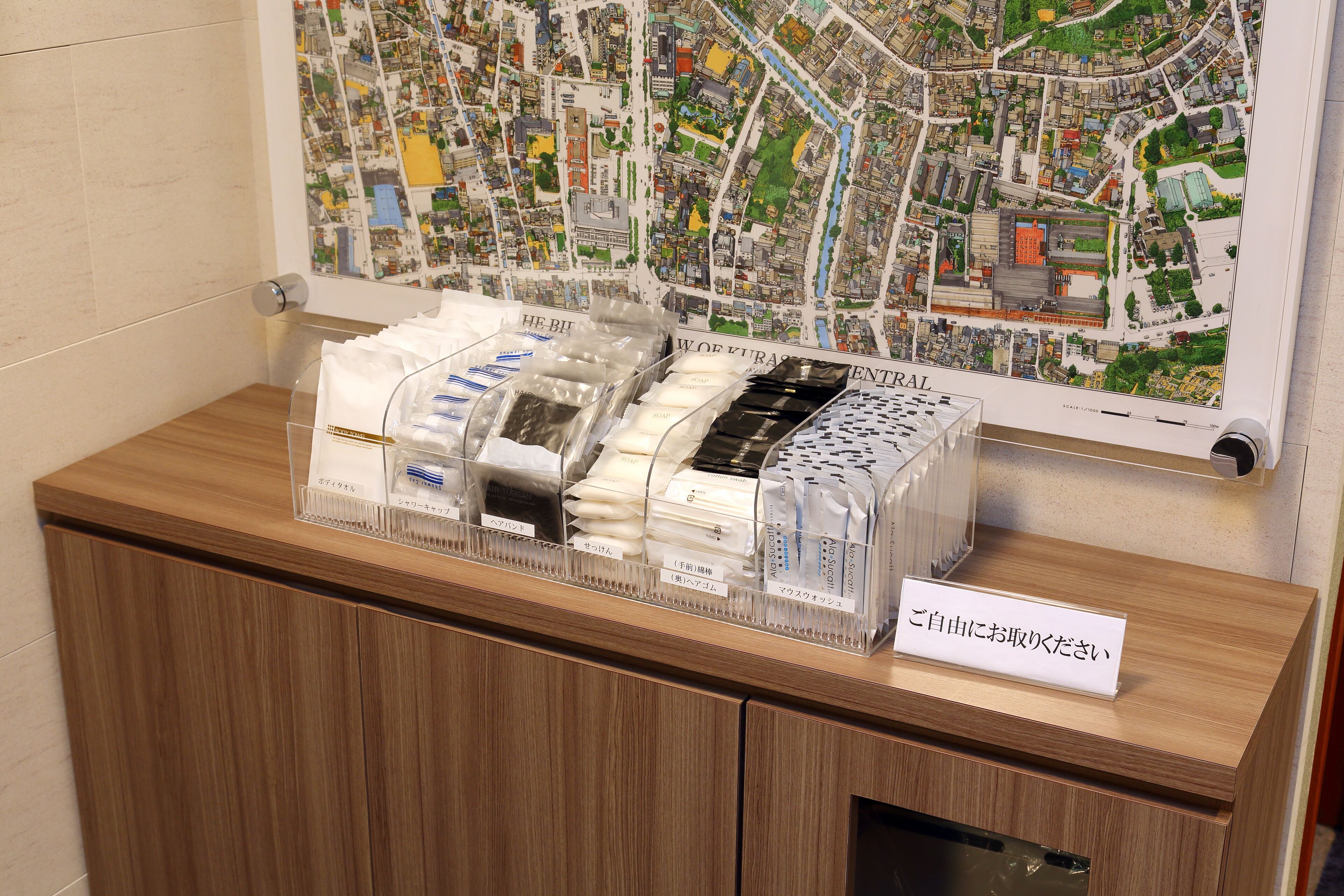 A hotel reception desk with a map of the city and a display of toiletries.