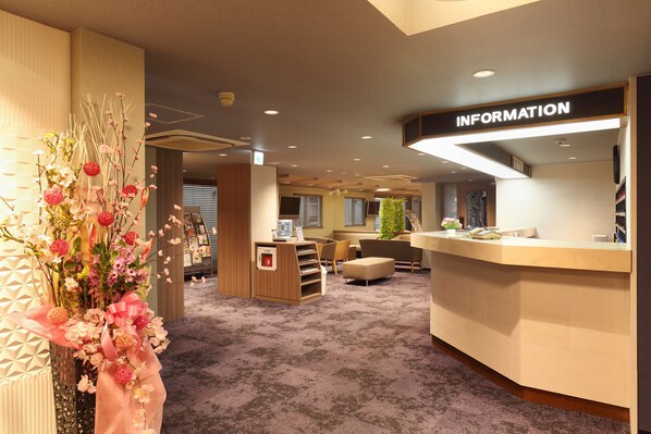 A reception area with a counter labeled "INFORMATION," a seating area with a plant, and a decorative floral arrangement. - Kurashiki Station Hotel (Kurashiki)