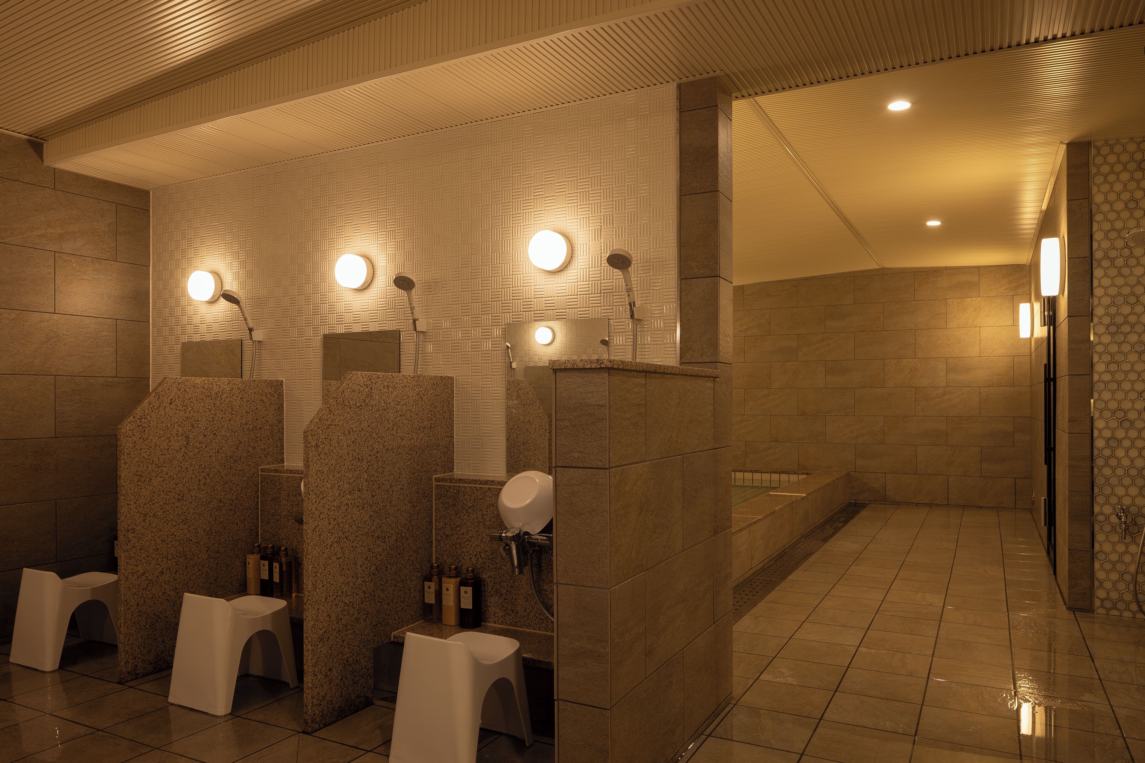 Des toilettes publiques avec plusieurs cabines, des lavabos et un espace douche.