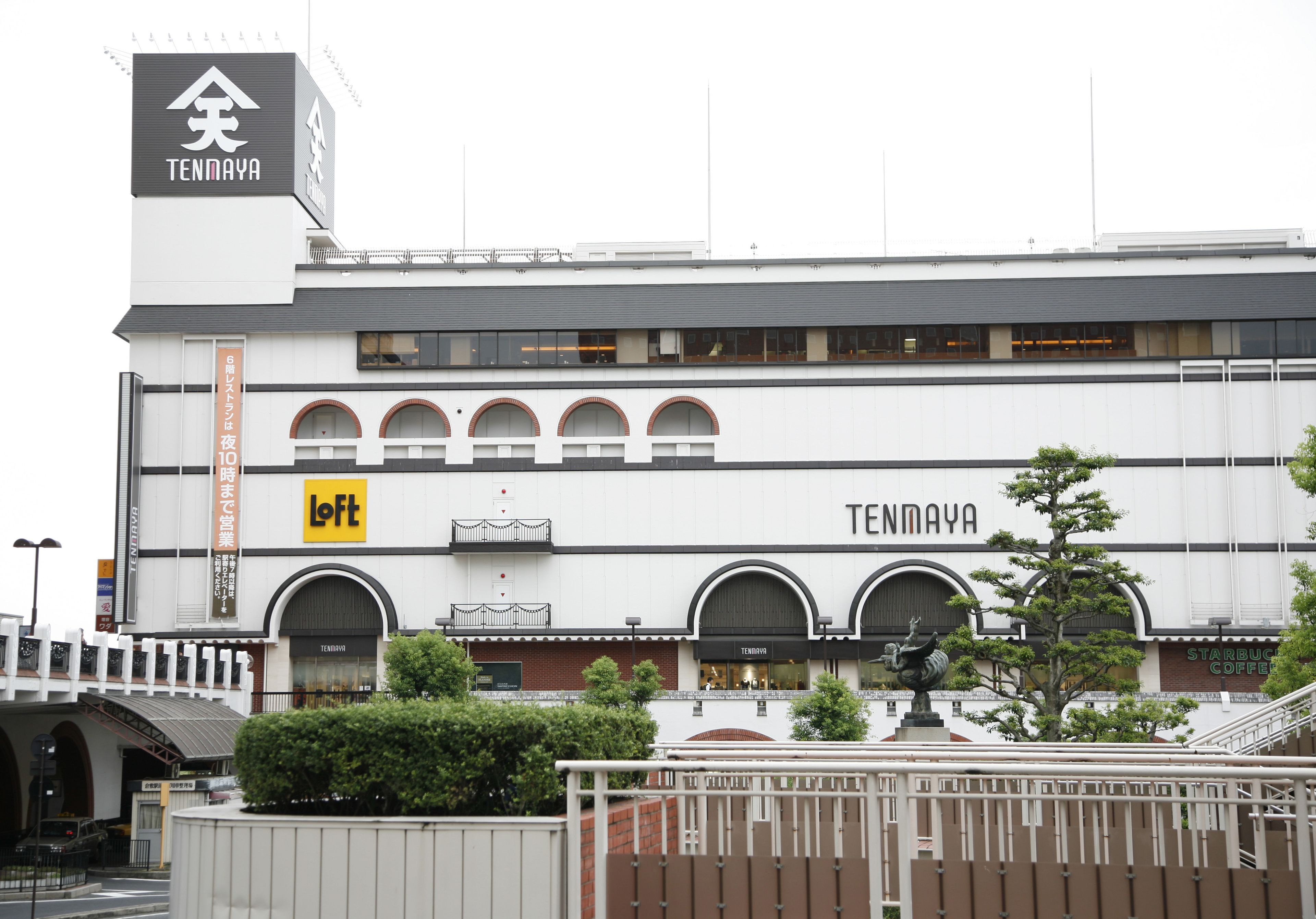 A modern building with a prominent 'Tennaya' sign, a 'Loft' store, and a Starbucks coffee shop.