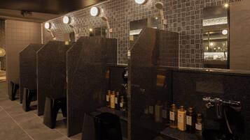 A row of dark granite sinks with mirrors above them, and a tiled wall with a geometric pattern.