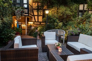 An outdoor patio area with wicker furniture, a stone bench, and a hanging flower arrangement. - Landhaus Alte Scheune (Frankfurt)