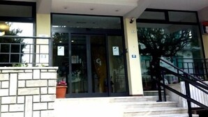 A building entrance with a covered porch, a staircase, and a brick wall with potted plants. - Hotel Gabbiano (Porto San Giorgio)