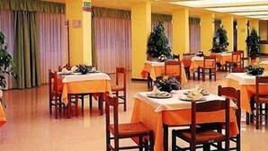 A dining area with tables and chairs, a Christmas tree, and a sign indicating the exit. - Hotel Gabbiano (Porto San Giorgio)