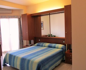 Ein Schlafzimmer mit Bett, Nachttisch, Spiegel und einem Fenster mit Vorhängen.