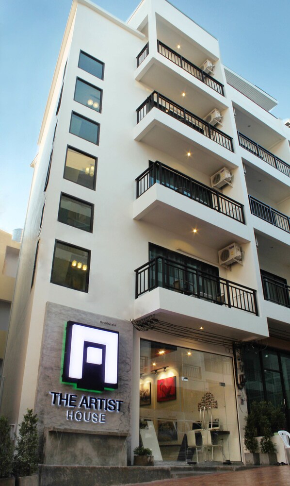 A modern building with multiple balconies, air conditioning units, and a sign reading "The Artist House".
