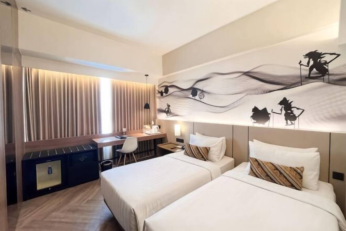 A hotel room with two beds, a desk, and a chair.
