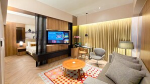 Een moderne hotelkamer met een televisie, een bank, fauteuil en een klein tafeltje.