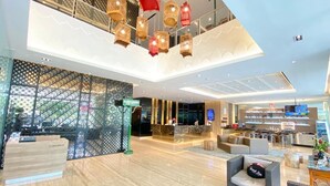 Un moderno vestíbulo de hotel con una recepción, zona de estar y un restaurante.