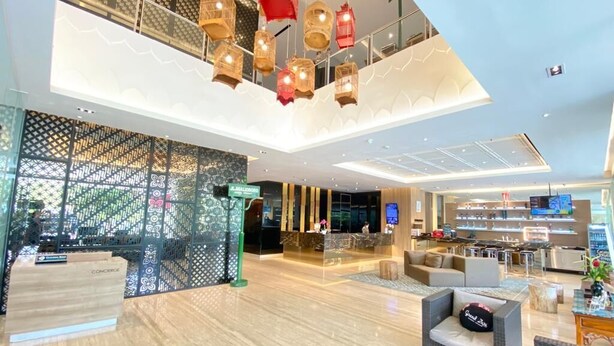 Een moderne hotelentree met een receptie, een zithoek en een restaurant.