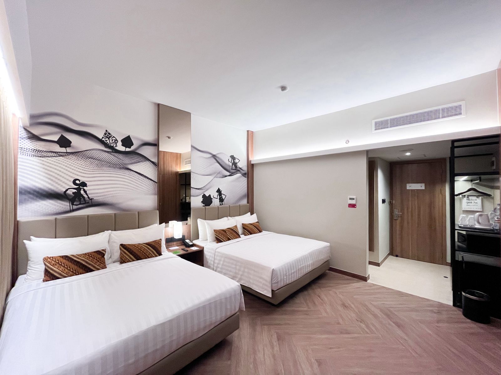 A hotel room with two beds, a wardrobe, and a mirror.