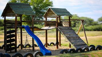 Kids can climb and slide in this outdoor play area with a wooden structure and green roof.