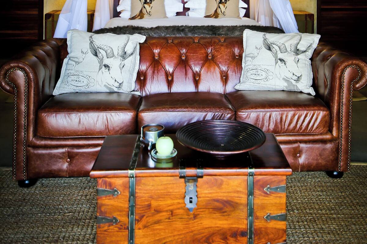 Une chambre à coucher avec un lit à baldaquin, un canapé en cuir et une commode en bois.