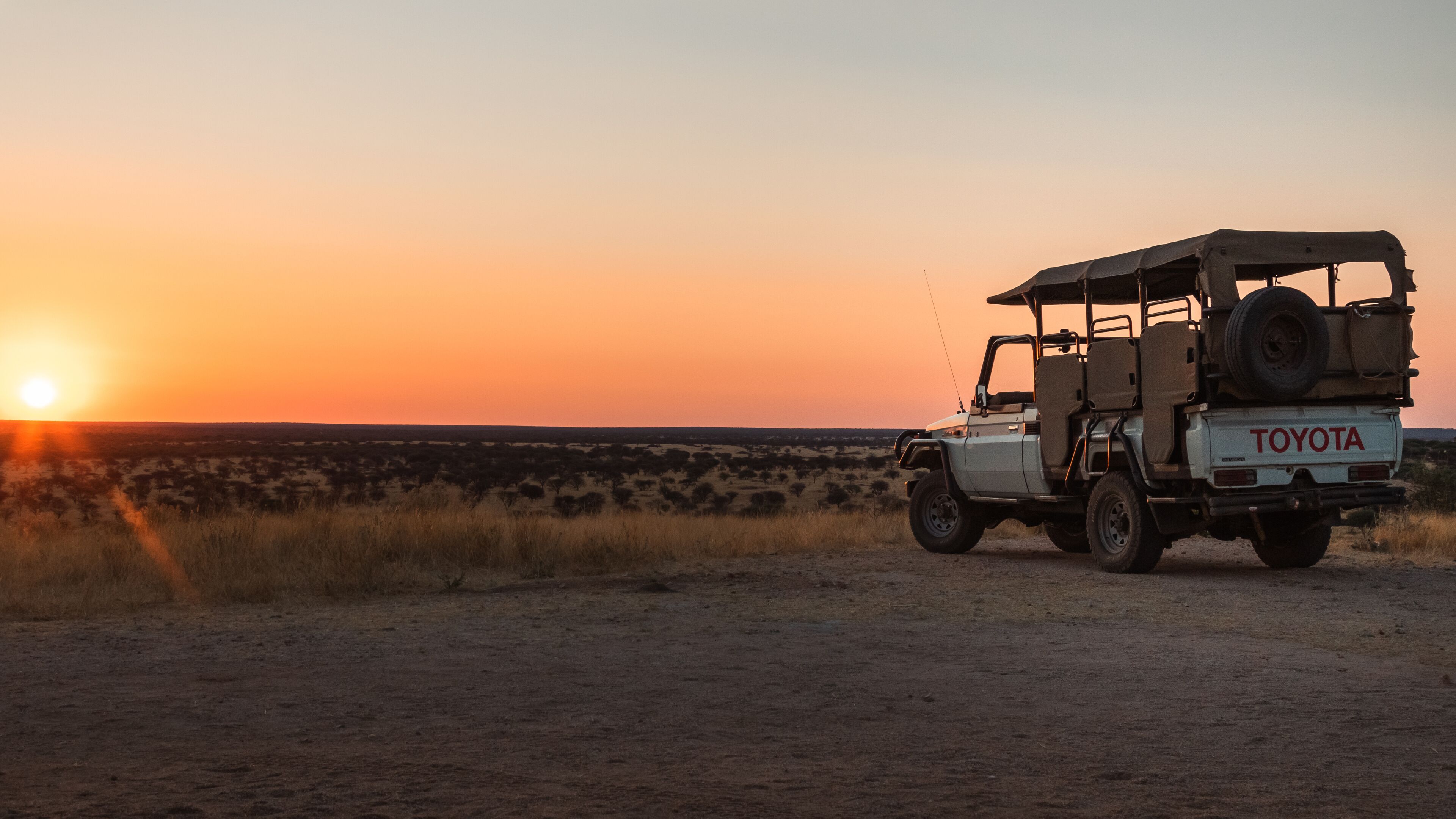 A Toyota off-road vehicle parked on a dirt road during sunset.