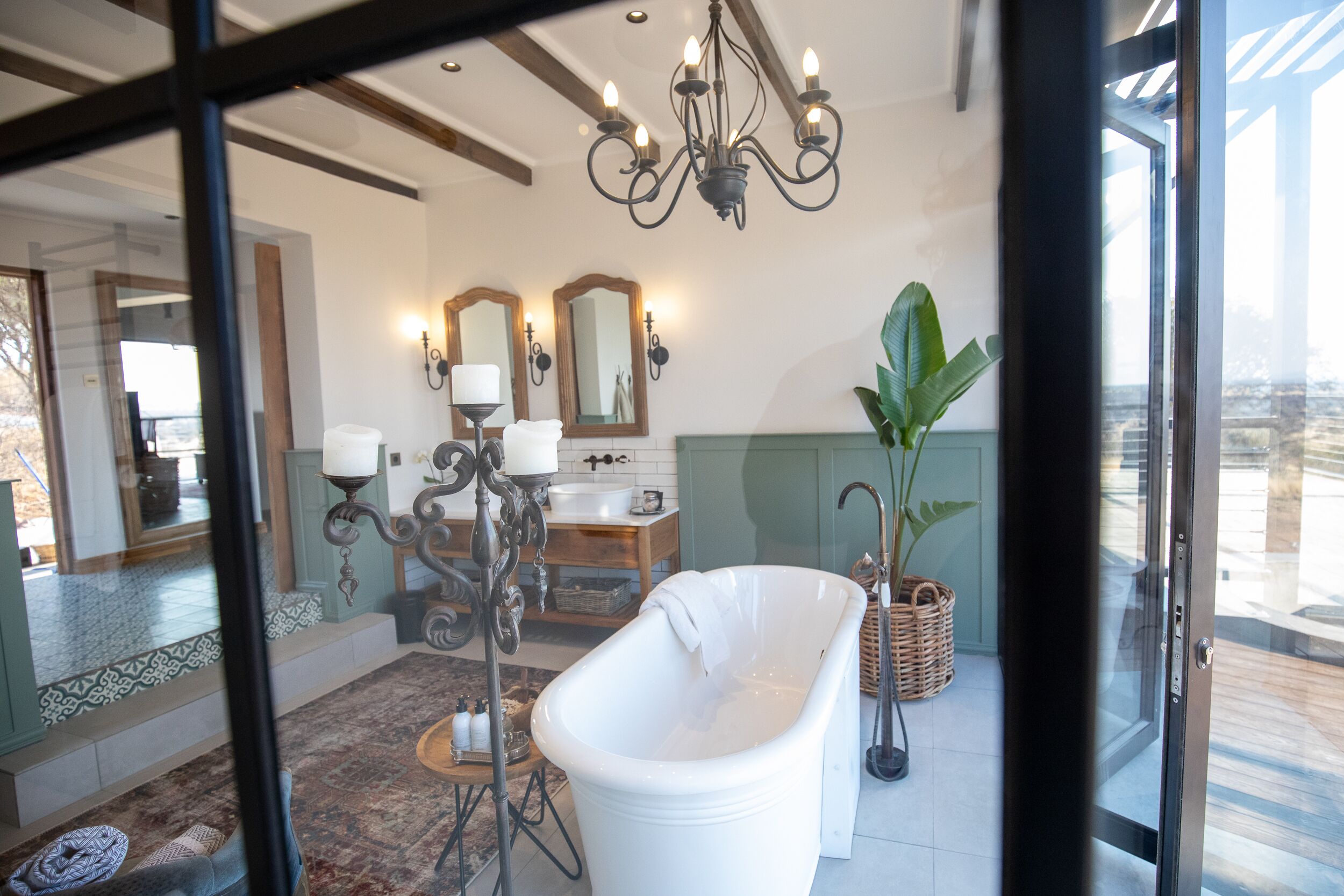 A bathroom with a freestanding bathtub, a vanity with a mirror, and a chandelier.