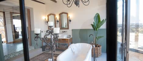 A bathroom with a freestanding bathtub, a vanity with a mirror, and a chandelier.