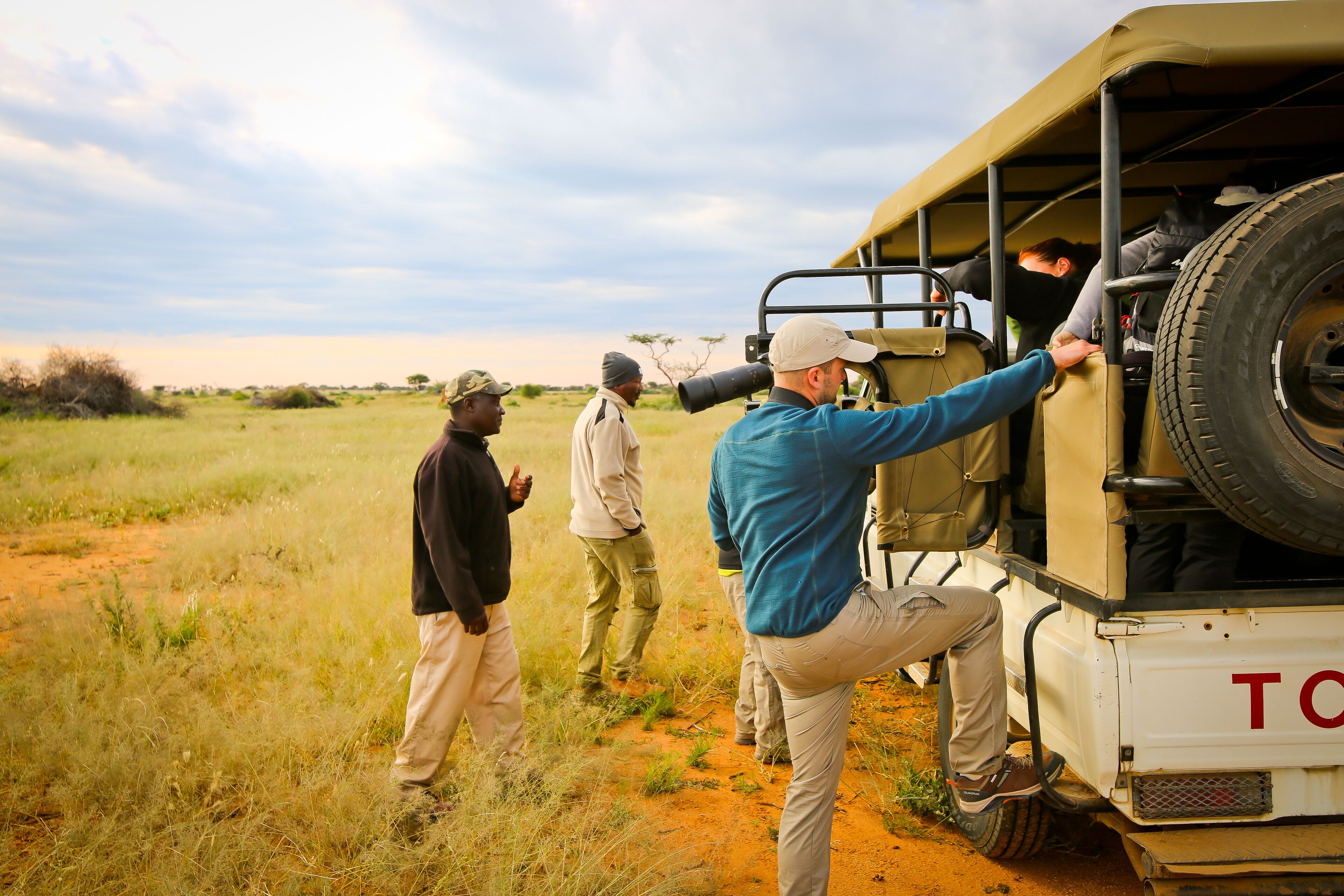 A group of people boarding a vehicle with a large spare tire.