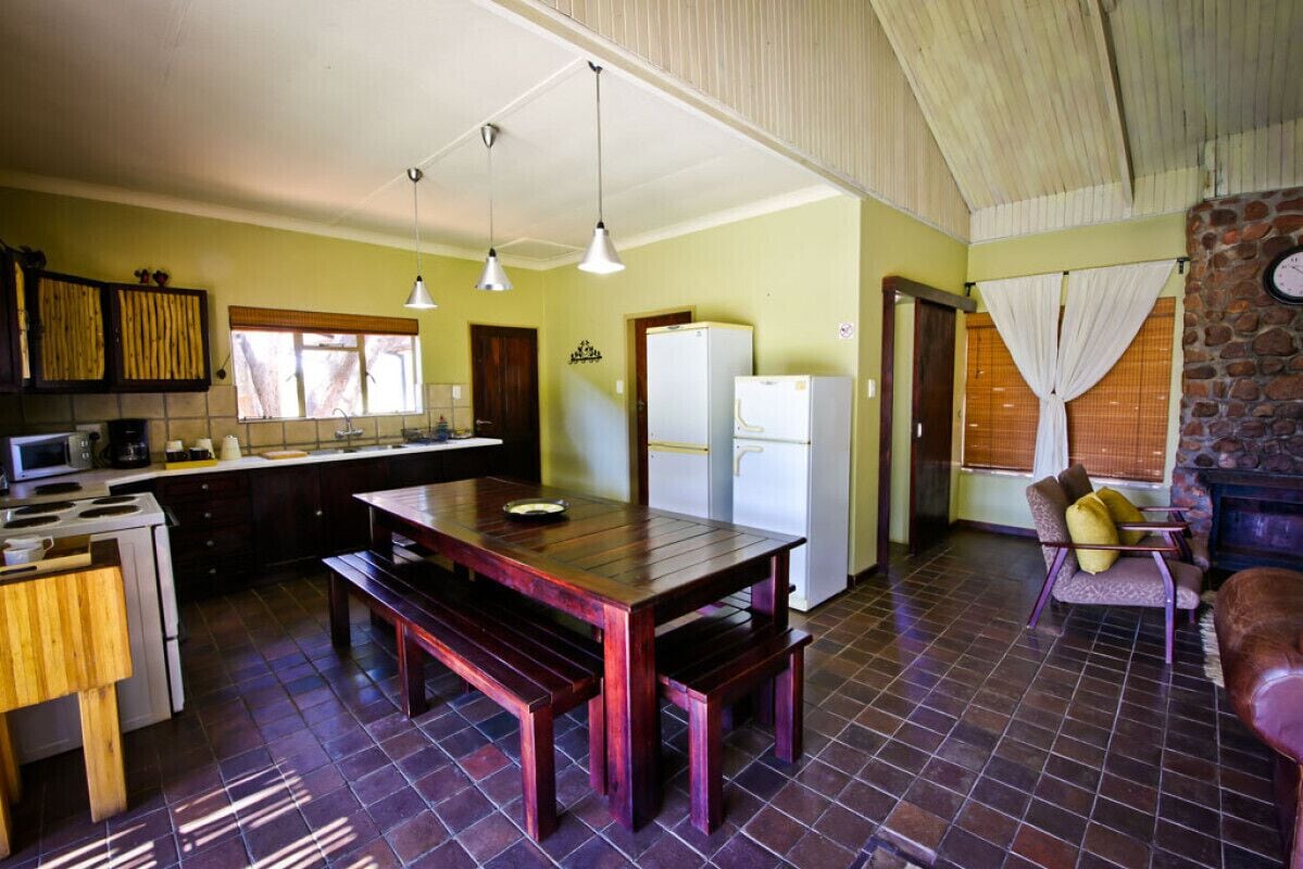 Una cocina con mesa y banco de madera, un refrigerador y un microondas.
