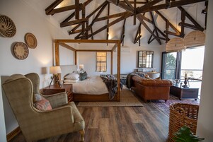 Un dormitorio amplio con cama con dosel, una sala de estar con sofá y sillón, y un comedor con mesa y sillas.