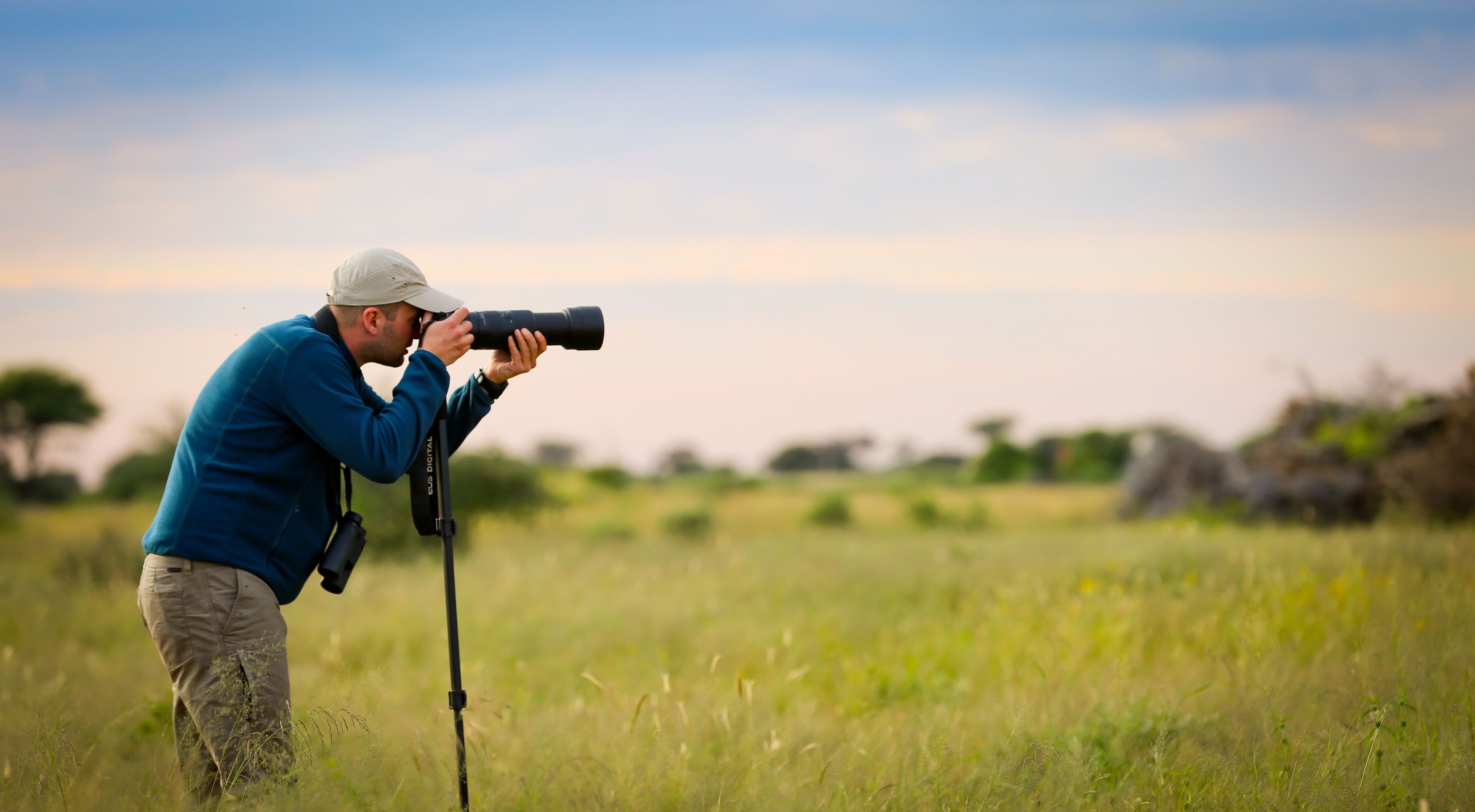 Een persoon gebruikt een camera in een grasveld.