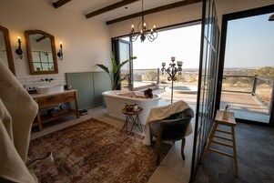 Un baño moderno con una bañera independiente, un espejo grande y vistas al exterior.