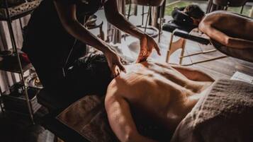 Experience a soothing massage in a serene space with a wooden massage table and expert therapist.