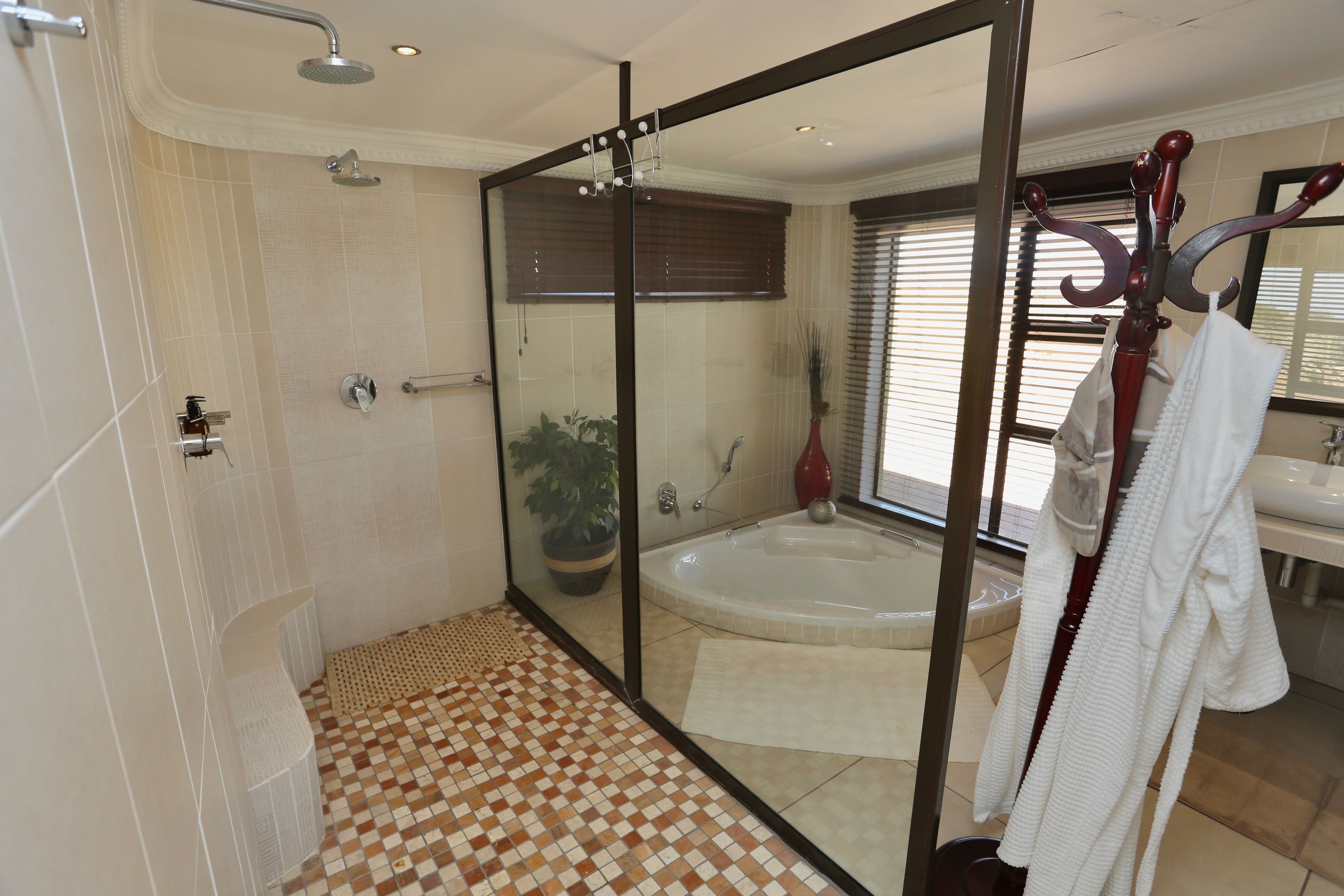 A modern bathroom with a glass-enclosed shower, a bathtub, and a large mirror.