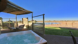 A hot tub with a wooden deck, outdoor seating, and a view of a lake. - Lapa Lange Game Lodge (Mariental)