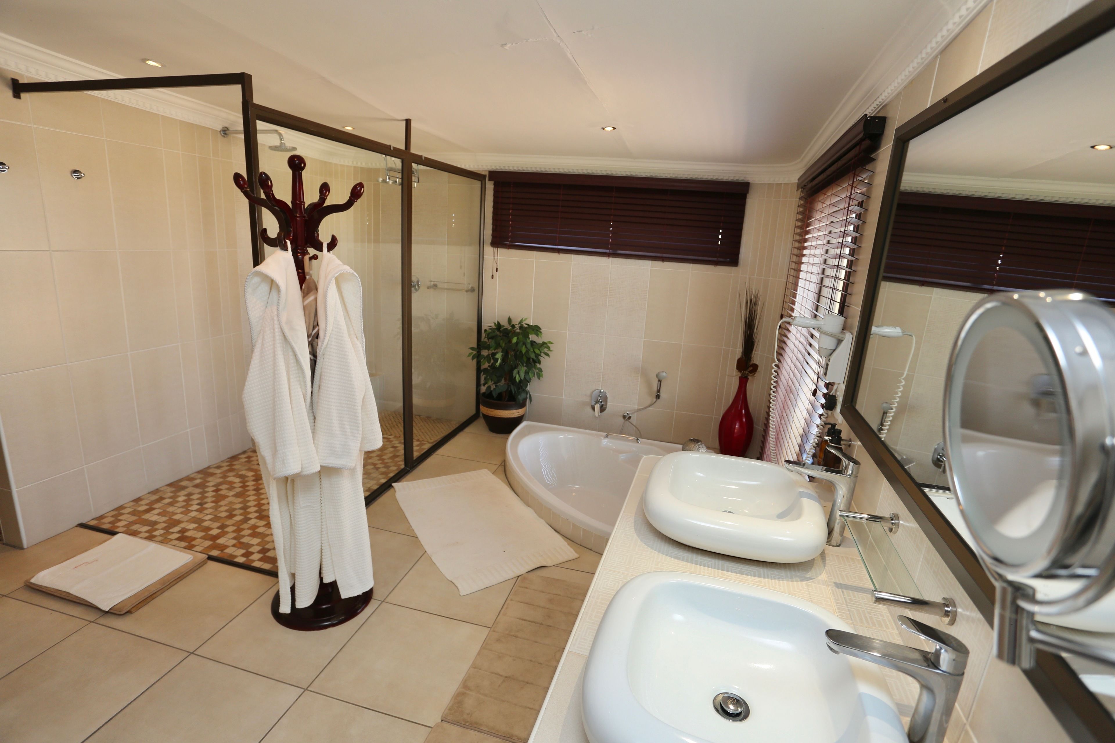 A modern bathroom with a glass-enclosed shower, a bathtub, and two sinks.