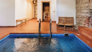A swimming pool with a wooden deck, a wooden bench, and a sauna area. - Fat Margaret's Hostel (Tallinn)