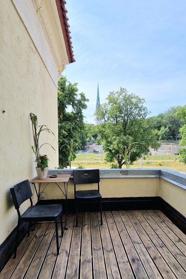 A balcony with two black chairs, a small table, and a potted plant. - Fat Margaret's Hostel (Tallinn)