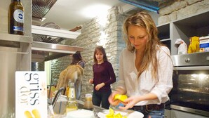 A kitchen with a stone wall, a microwave, and a person preparing food. - Fat Margaret's Hostel (Tallinn)