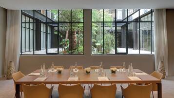 A conference room with a long table set for meetings, large windows with a view of greenery, and traditional decor.
