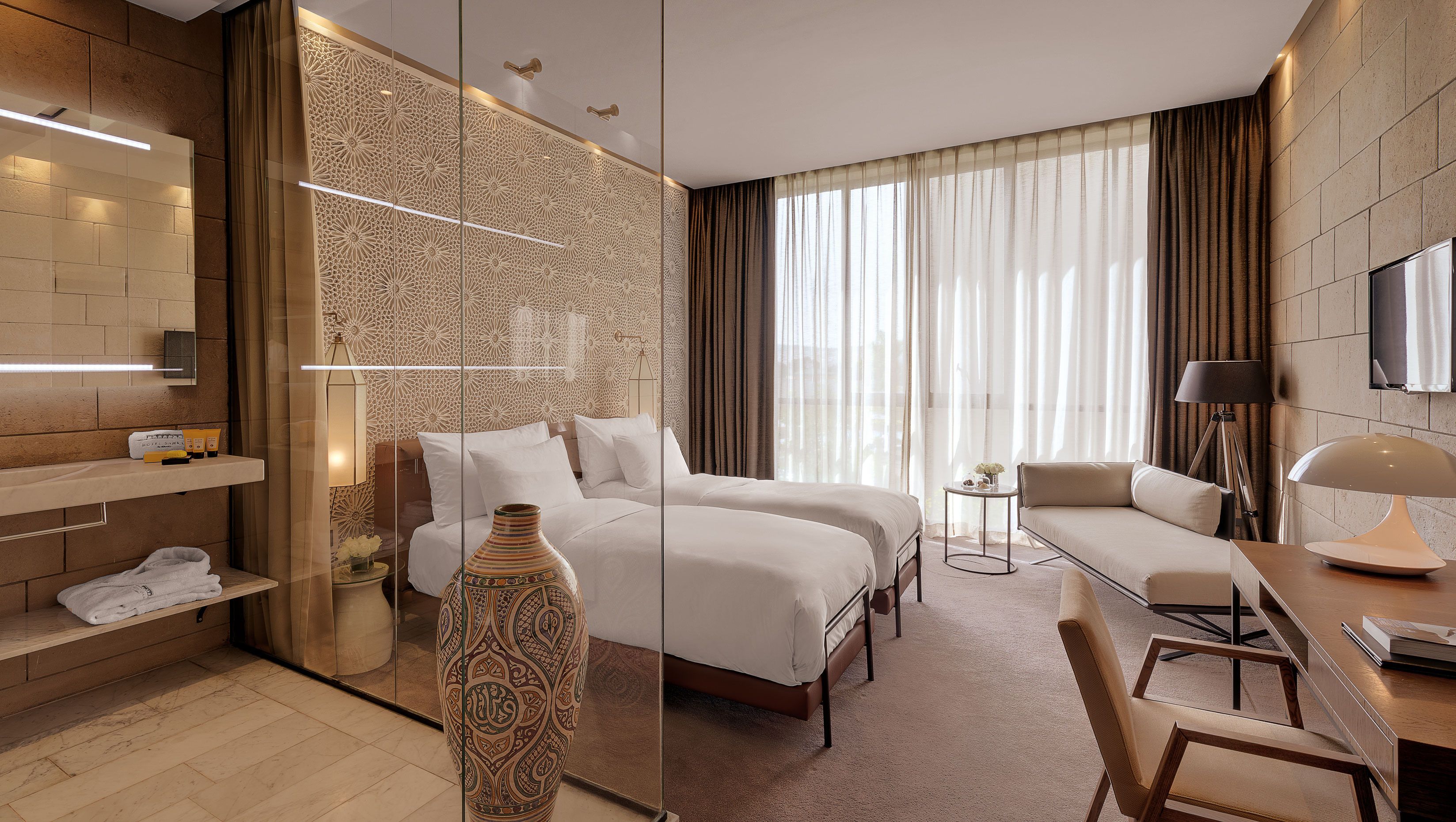 Ein modernes Hotelzimmer mit einem großen Bett, einer Sitzecke, einem Schreibtisch und einem Badebereich.