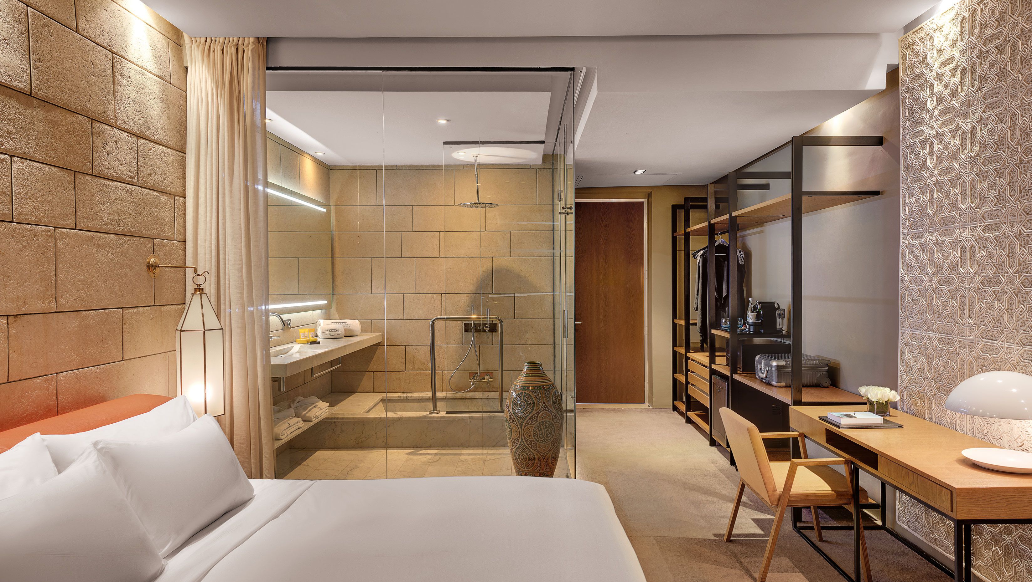Une chambre d’hôtel moderne équipée d’un lit, d’un bureau, d’une douche et d’un meuble-lavabo.