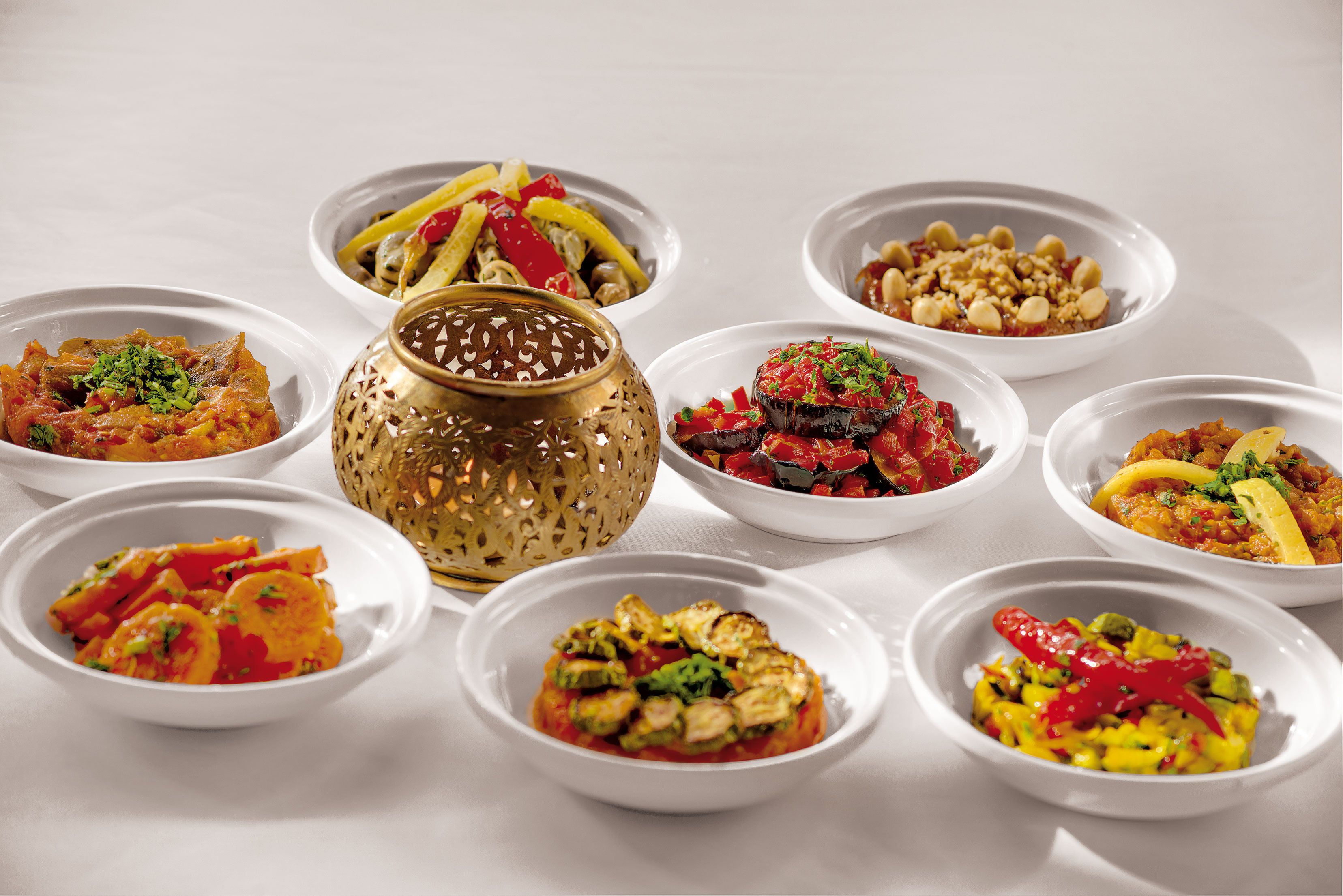 Une table avec différents plats servis dans des bols, un vase décoratif doré et un bol à motifs.