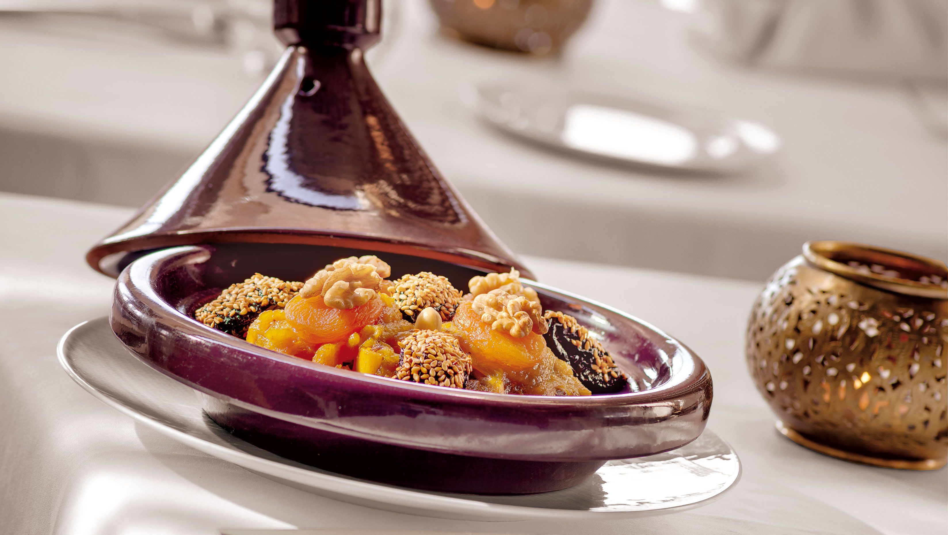 Um prato tradicional marroquino de tagine com nozes e frutas secas sobre um prato de cerâmica.