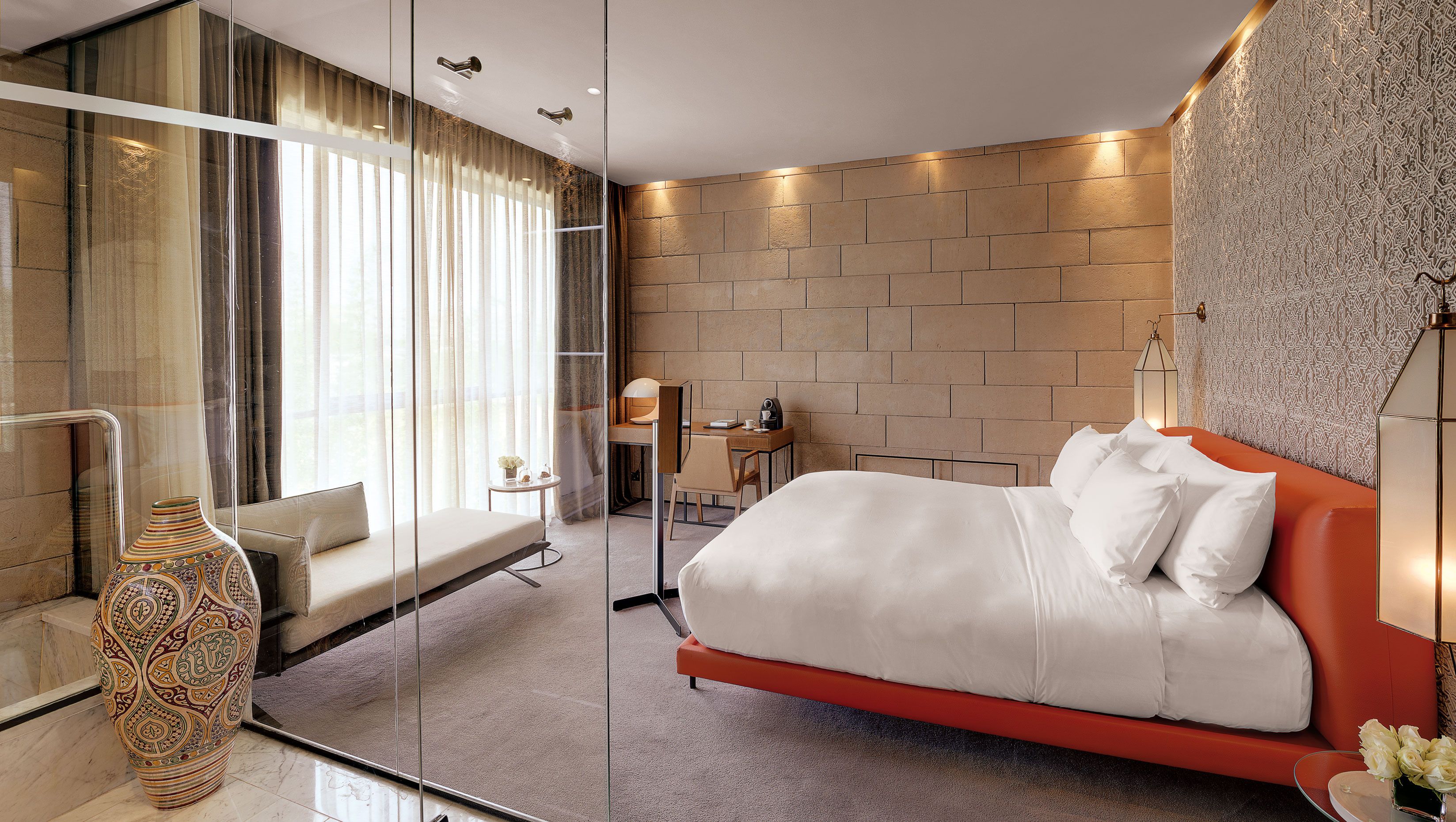 Una camera d'albergo moderna con un letto grande, una scrivania, una sedia e un vaso.