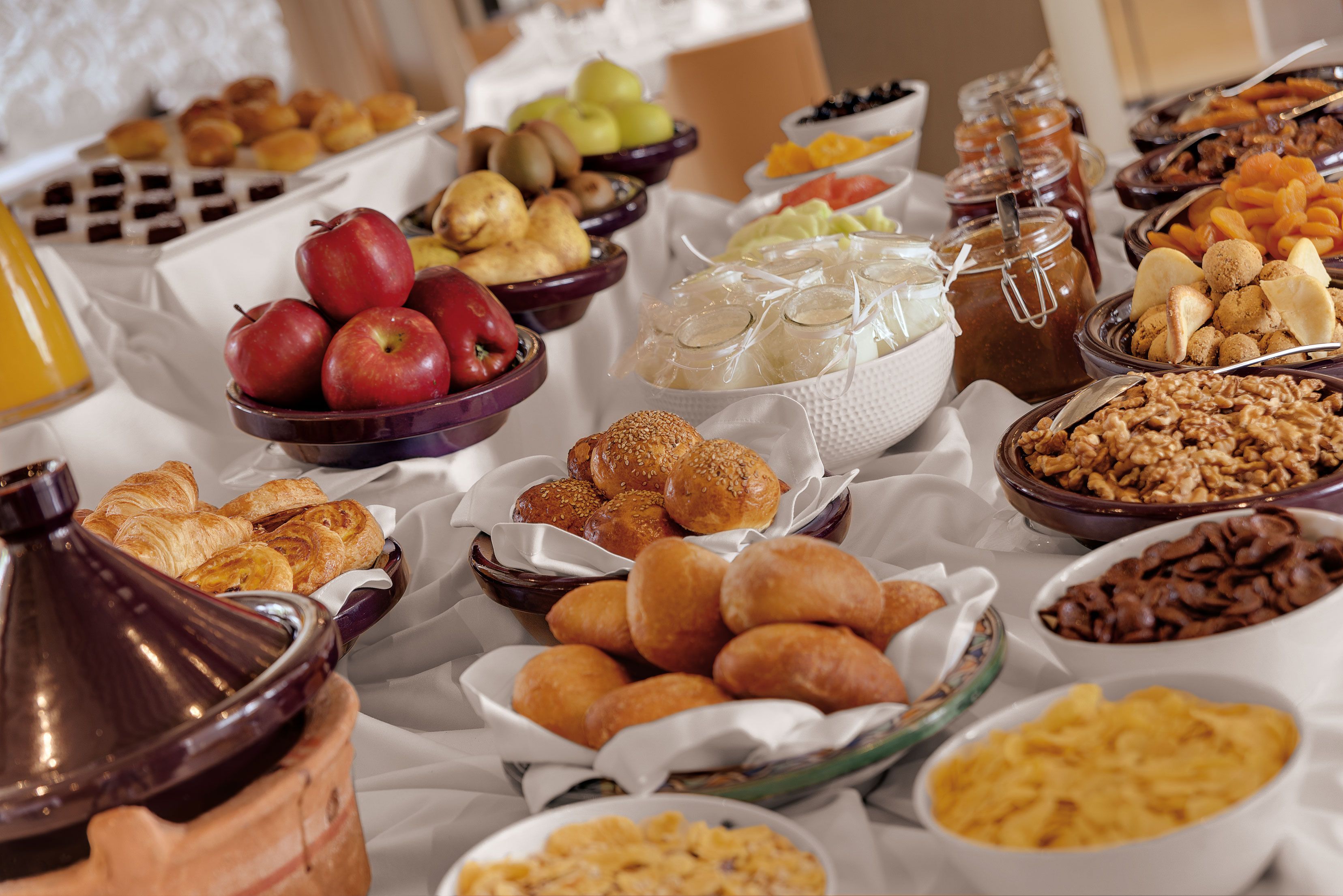 A buffet with various food items including fruits, pastries, and condiments.