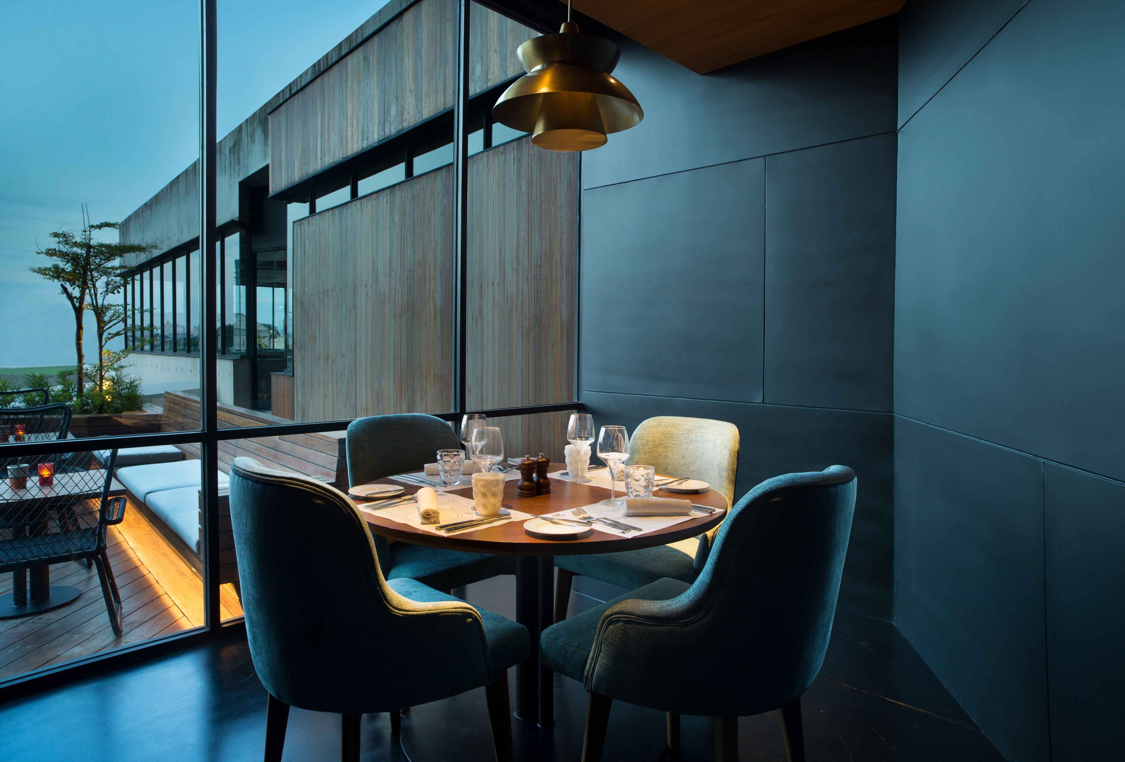A modern dining area with a round table, four chairs, and a hanging light fixture.
