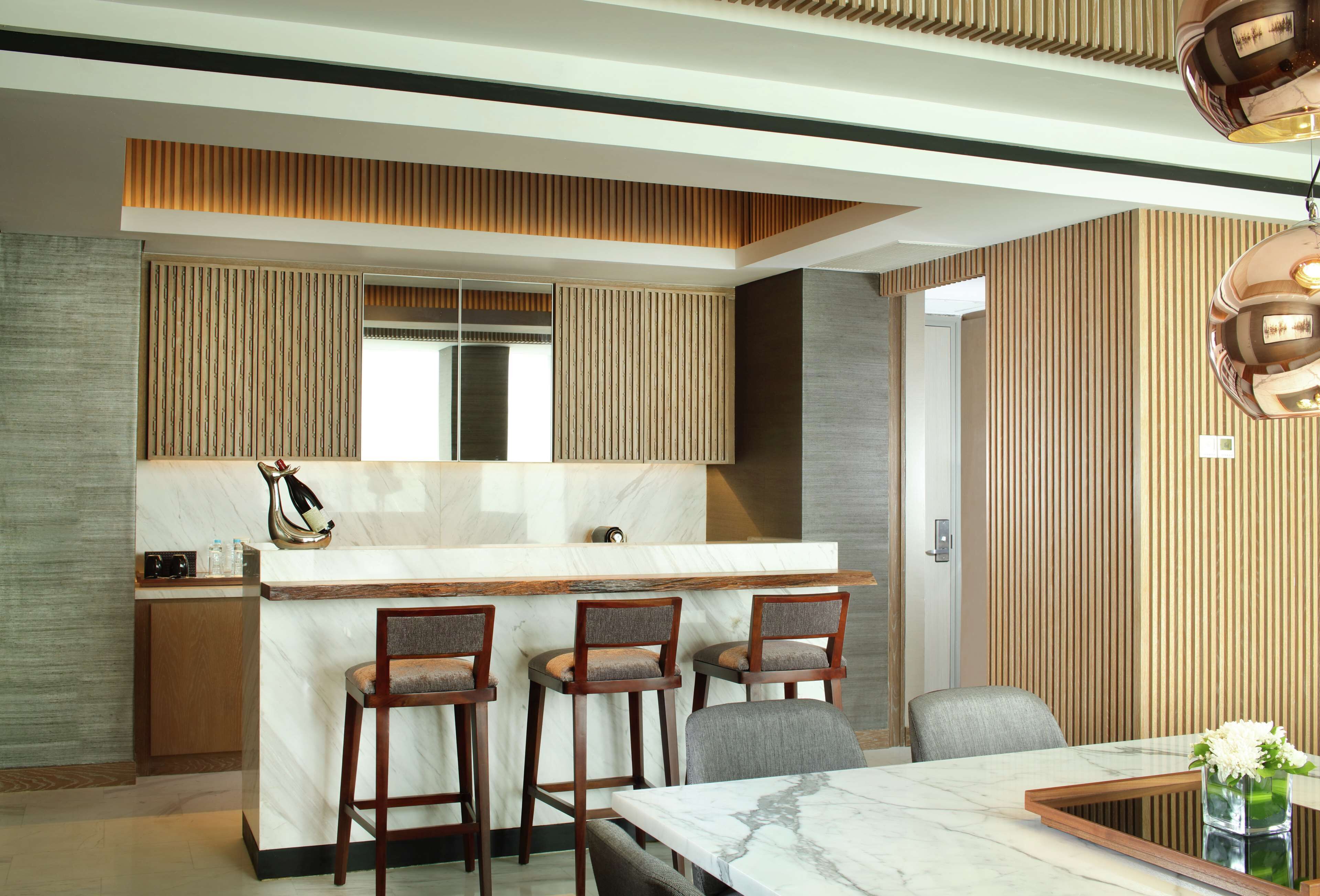 Una cocina moderna con encimera de mármol, taburetes de madera y una mesa de comedor con sillas.