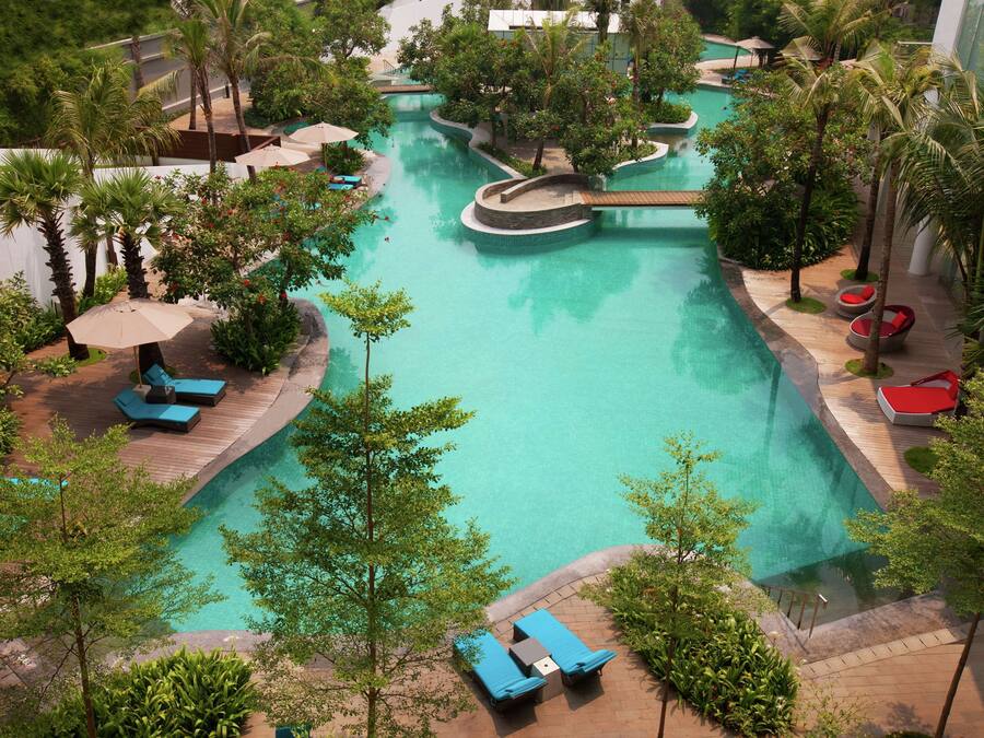 A resort pool area with multiple lounge chairs and a winding pool design.