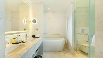 Un baño moderno con un espejo grande, dos lavamanos, una bañera y zona de ducha con mampara de vidrio.