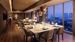 Un comedor moderno con una mesa grande preparada para seis personas, un sofá y vistas a la ciudad.