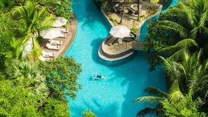An aerial view of a resort with a central swimming pool, surrounded by palm trees and lounge areas. - DoubleTree by Hilton Jakarta - Diponegoro (Jakarta)