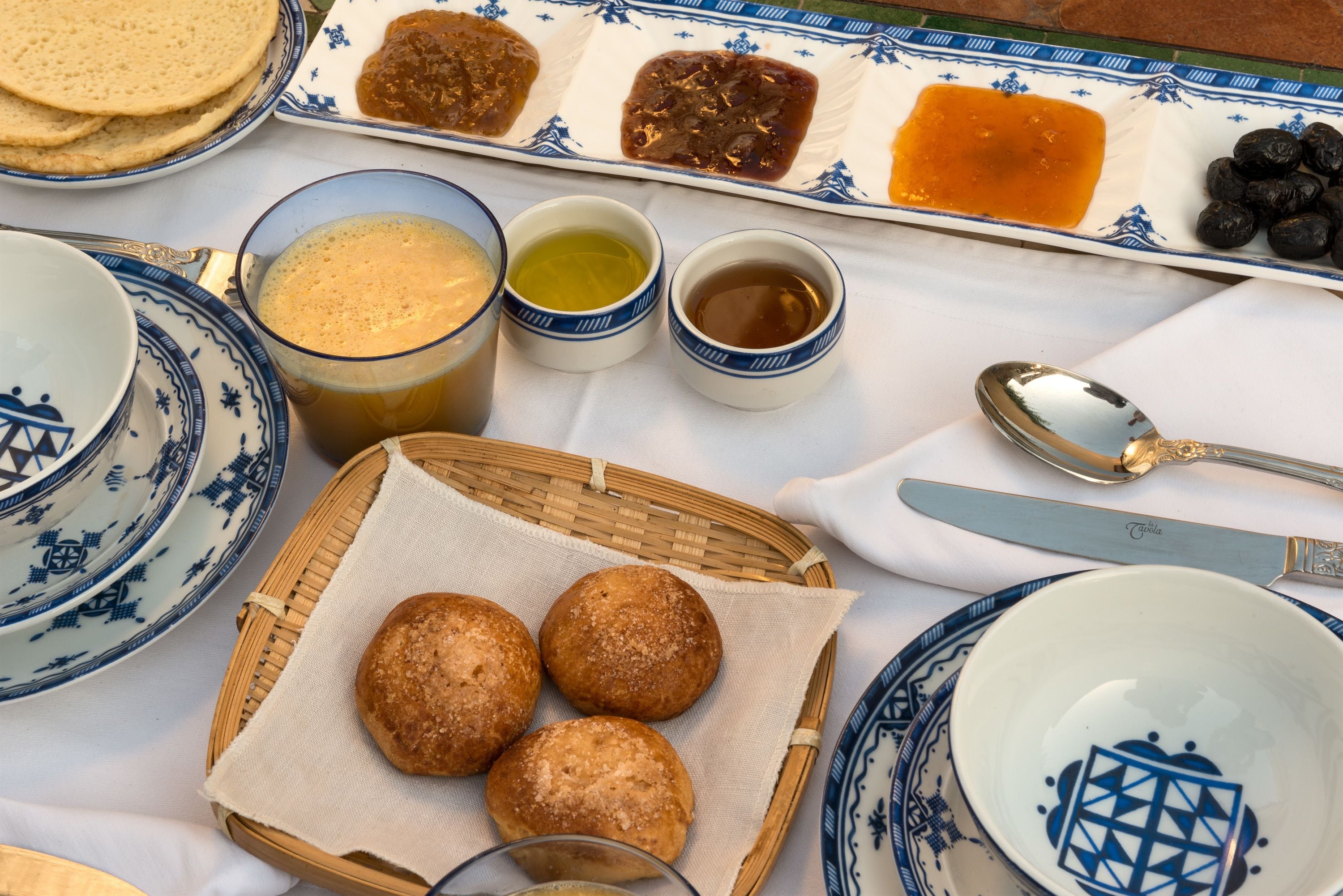 Una mesa con diversos alimentos, entre ellos pan, mermeladas y bebidas.
