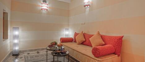 A cozy living room with a sofa, patterned rug, and decorative wall sconces.