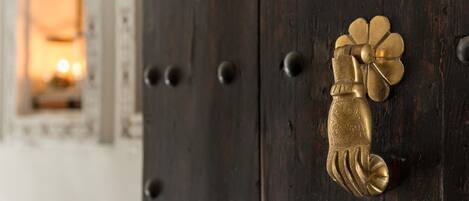 A brass door knocker with a floral design on a dark wooden door.