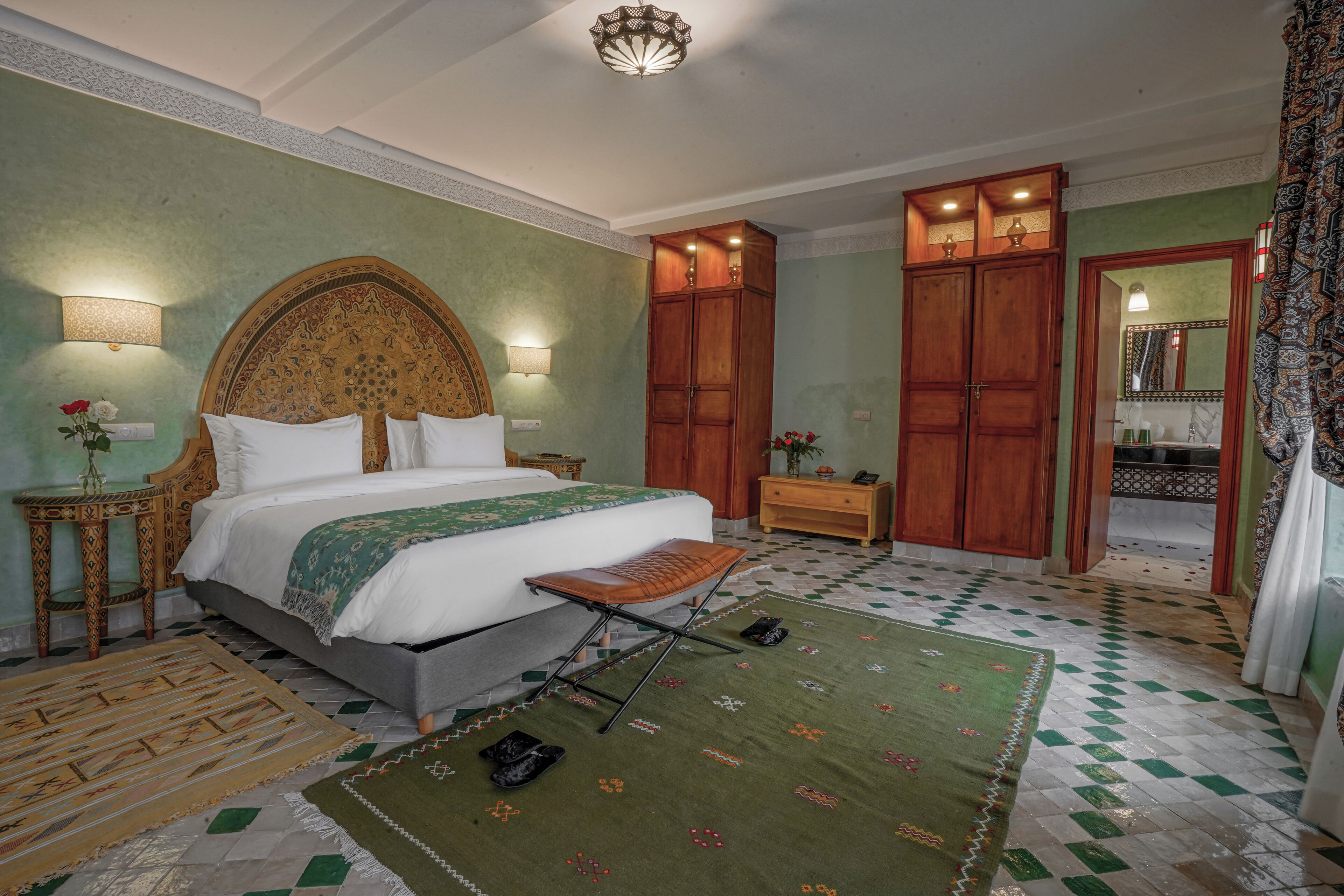 Une chambre avec un grand lit, une armoire en bois et un tapis à motifs verts.