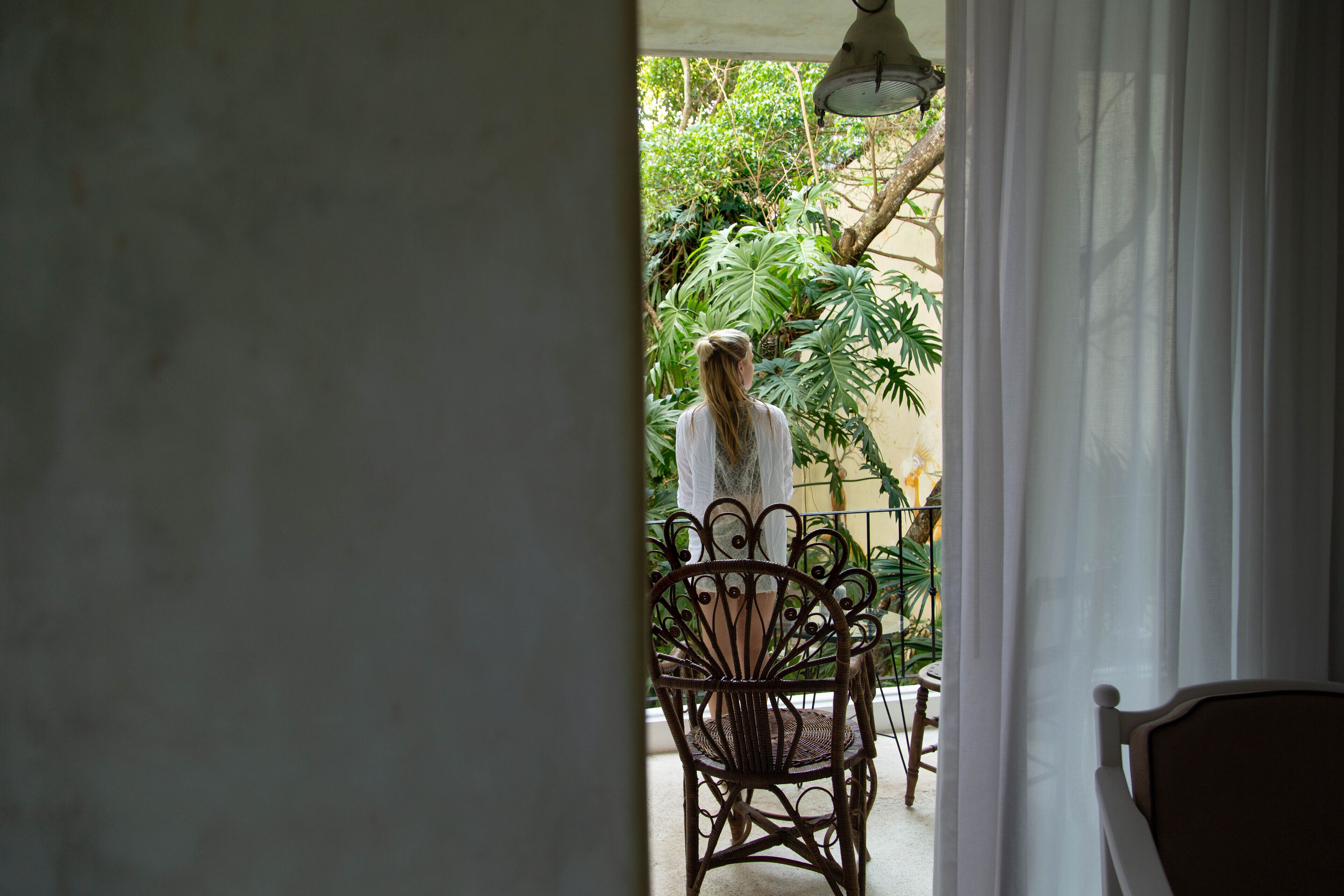 Vista di un balcone con una sedia e un tavolo, immerso nel verde.